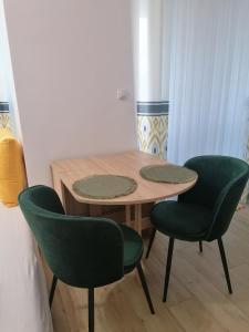 a table and two green chairs in a room at Студио Ели - Пловдив in Plovdiv