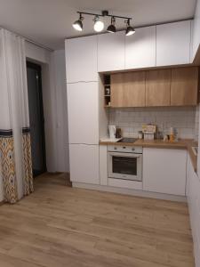 a kitchen with white cabinets and a wooden floor at Студио Ели - Пловдив in Plovdiv