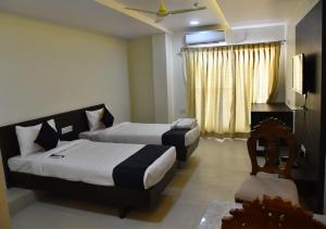 a hotel room with two beds and a television at Swarna Palace in Siddipet