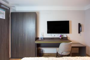 Habitación con escritorio y TV en la pared. en ASD Hotel en Filderstadt