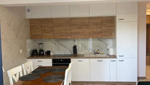 a kitchen with white cabinets and a table with chairs at Apartament Zielony 12/2 in Starogard Gdański