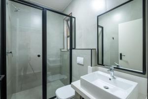 a white bathroom with a sink and a shower at Inn & Out Plus Rosebank in Johannesburg