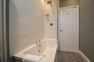 a white bathroom with a tub and a shower at Fairways View - Spacious Apartment - Sleeps 6 - Lovely Views in Hoylake