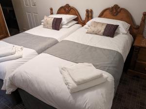 two beds in a bedroom with white sheets and pillows at The Board Inn - Lealholm in Whitby