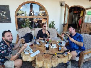 three men sitting around a table eating food at HARRIS HOTEL Y RESTAURANTE in Licán Ray