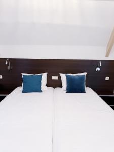 two beds with blue pillows sitting next to each other at Hotel de Magneet in Hoorn