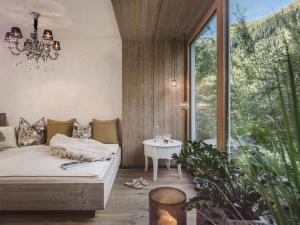 a bedroom with a bed and a table and a window at Hotel Bergkristall Zillertal - Adults Only in Hippach