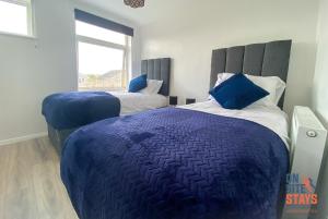 1 Schlafzimmer mit 2 Betten und blauen Kissen in der Unterkunft OnSiteStays - Ideal Long Term Retreat, 2-BR House with Conservatory, Parking & Wi-Fi in Canterbury