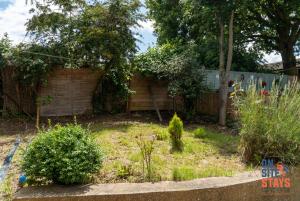 einen Garten mit einem Zaun und einigen Büschen und Bäumen in der Unterkunft OnSiteStays - Ideal Long Term Retreat, 2-BR House with Conservatory, Parking & Wi-Fi in Canterbury