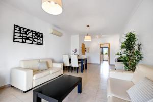 Una sala de estar con muebles blancos y una mesa. en Chez Hélène et Paulo - Lagos, en Lagos