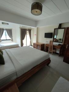 a bedroom with two beds and a desk and a television at Chivapuri Trat in Trat