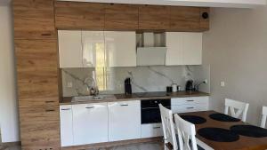 a kitchen with white cabinets and a table with chairs at Apartament Niebieski 14/1 in Starogard Gdański +4 photos