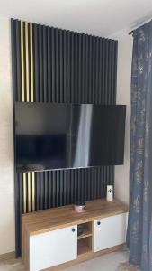 Une grande télévision à écran plat est installée au-dessus d'une table. dans l'établissement Apartament Niebieski 14/1, à Starogard Gdański