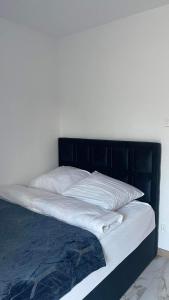 - un lit avec des draps blancs et une tête de lit noire dans l'établissement Apartament Niebieski 14/1, à Starogard Gdański