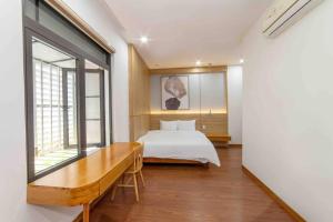 1 dormitorio con cama, escritorio y ventana en Villa Hero 5 bed roooms near beach, luxury swimming pool, en Da Nang