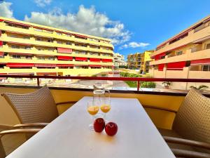 two glasses of wine and two cherries on a table on a balcony at Kpaco Apartment in Puerto de Santiago