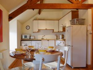 a kitchen with a table and a white refrigerator at Granary Cottage in Oswestry