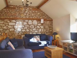 a living room with a blue couch and a stone wall at Granary Cottage in Oswestry