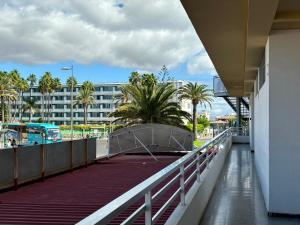 - un balcon dans un bâtiment avec des palmiers et un bus dans l'établissement Loris Home playa ingles 50mt from Yumbo by luca properties gran canaria, à San Bartolomé