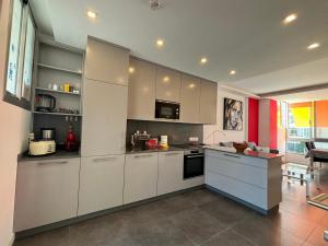 a kitchen with white cabinets and a red wall at Loris Home playa ingles 50mt from Yumbo by luca properties gran canaria in San Bartolomé de Tirajana