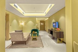 Green Park Hotel في الدوحة: غرفة معيشة فيها كنب وكرسي وتلفزيون