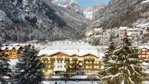 um hotel nas montanhas com neve no chão em Alledolomiti Boutique Lake Hotel - Adults friendly em Molveno