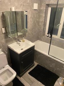 a bathroom with a sink and a toilet and a tub at Spacious family friendly 3 bedroom Home With Hot tub & 75tv in Potters Bar