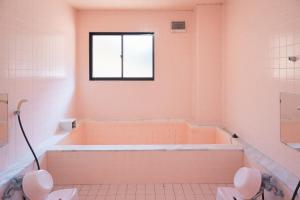 豊島ロッヂooバス停浅貝上前 في يوزاوا: حمام وردي مع حوض استحمام ونافذة