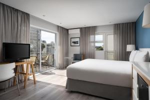 ein Hotelzimmer mit einem Bett, einem Schreibtisch und einem TV in der Unterkunft Protea Hotel by Marriott Cape Town Sea Point in Kapstadt