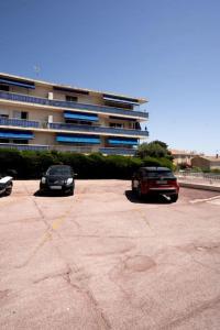 2 voitures garées sur un parking en face d'un immeuble dans l'établissement Appartement avec jardin proche mer, à Antibes