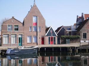 a boat sitting in the water in front of buildings at Hotel de Magneet in Hoorn