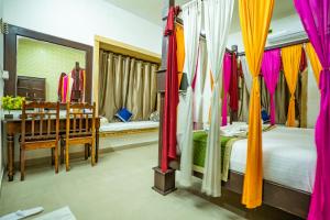 um quarto com uma cama com cortinas coloridas e uma mesa em Hotel Marina Mahal with Swimming Pool em Jaisalmer