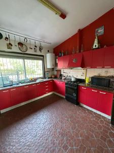 een keuken met rode kasten en een zwarte kachel bij Casa Corral Terra in Coronel Moldes