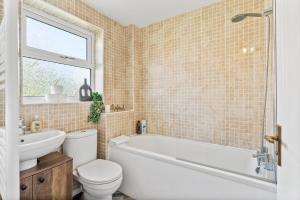 ein Badezimmer mit einer Badewanne, einem WC und einem Waschbecken in der Unterkunft Beautiful House in Cambridge - Sleeps 6 in Milton