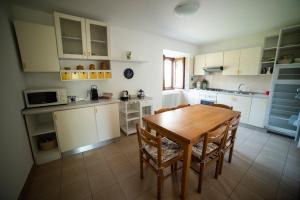 una cocina con armarios blancos y una mesa y sillas de madera. en Cascina Pirondini, en San Cassiano