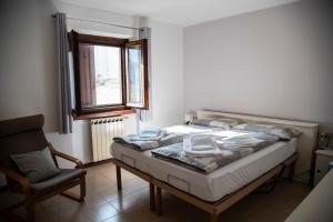 a bedroom with a bed and a chair and a window at Cascina Pirondini in San Cassiano