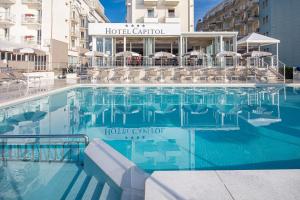 ein Pool mit Stühlen und ein Hotel in der Unterkunft Hotel Capitol in Lido di Jesolo