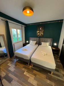 a bedroom with two beds and a green wall at Le Dauphin - Appartement chaleureux proche Gare de Bourgoin in Jallieu
