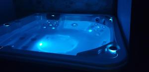 una bañera azul con luces en una habitación oscura en Chambre d'hôte romantique avec SPA privatif domaine les nuits envôutées - Vézénobres, en Vézénobres