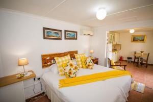 1 dormitorio con 1 cama grande con almohadas amarillas en Homestead Bed and Breakfast, en Addo