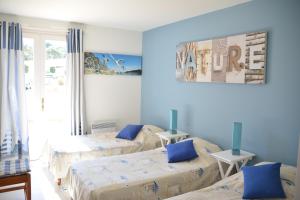 Cette chambre comprend 3 lits aux murs bleus. dans l'établissement Les Floralies, à La Tranche-sur-Mer
