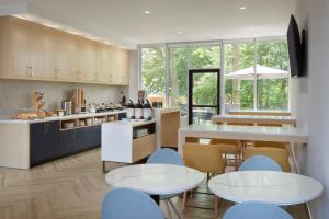 uma cozinha com armários brancos e cadeiras e mesas azuis em TownePlace Suites by Marriott Toronto Oakville em Oakville