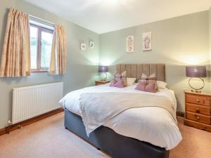 a bedroom with a large bed with pink pillows at Walnut Cottage - Uk45579 in Maltby le Marsh