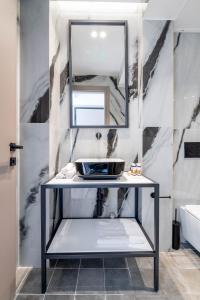 une salle de bain avec un lavabo et un miroir dans l'établissement ERMOU 40 SUITES, à Athènes
