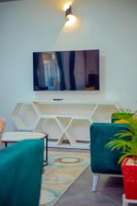 ein Wohnzimmer mit einem TV und einem blauen Stuhl in der Unterkunft Mpala Haven Entebbe in Entebbe