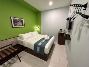 a bedroom with a bed and a green wall at R Hotel Langkawi in Kuah