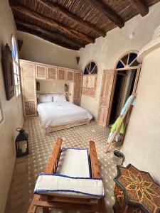 een slaapkamer met een bed en een tafel en banken bij Beau riad en médina, lumineux et avec terrasse privée sur mer in Essaouira