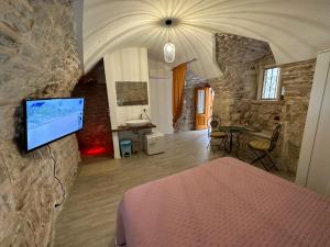 una camera con letto e TV su un muro di pietra di Giovinazzo Suite Pavone Griffi a Giovinazzo