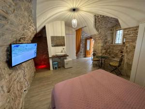 a bedroom with a bed and a tv on a stone wall at Giovinazzo Suite Pavone Griffi in Giovinazzo