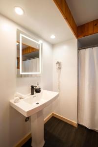 La salle de bains blanche est pourvue d'un lavabo et d'une douche. dans l'établissement Town House Lodge, à Lake Placid